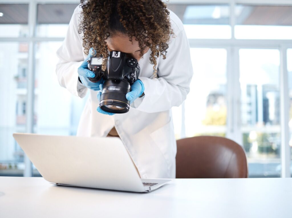 Science investigation, camera and black woman with laptop in laboratory for forensic research with